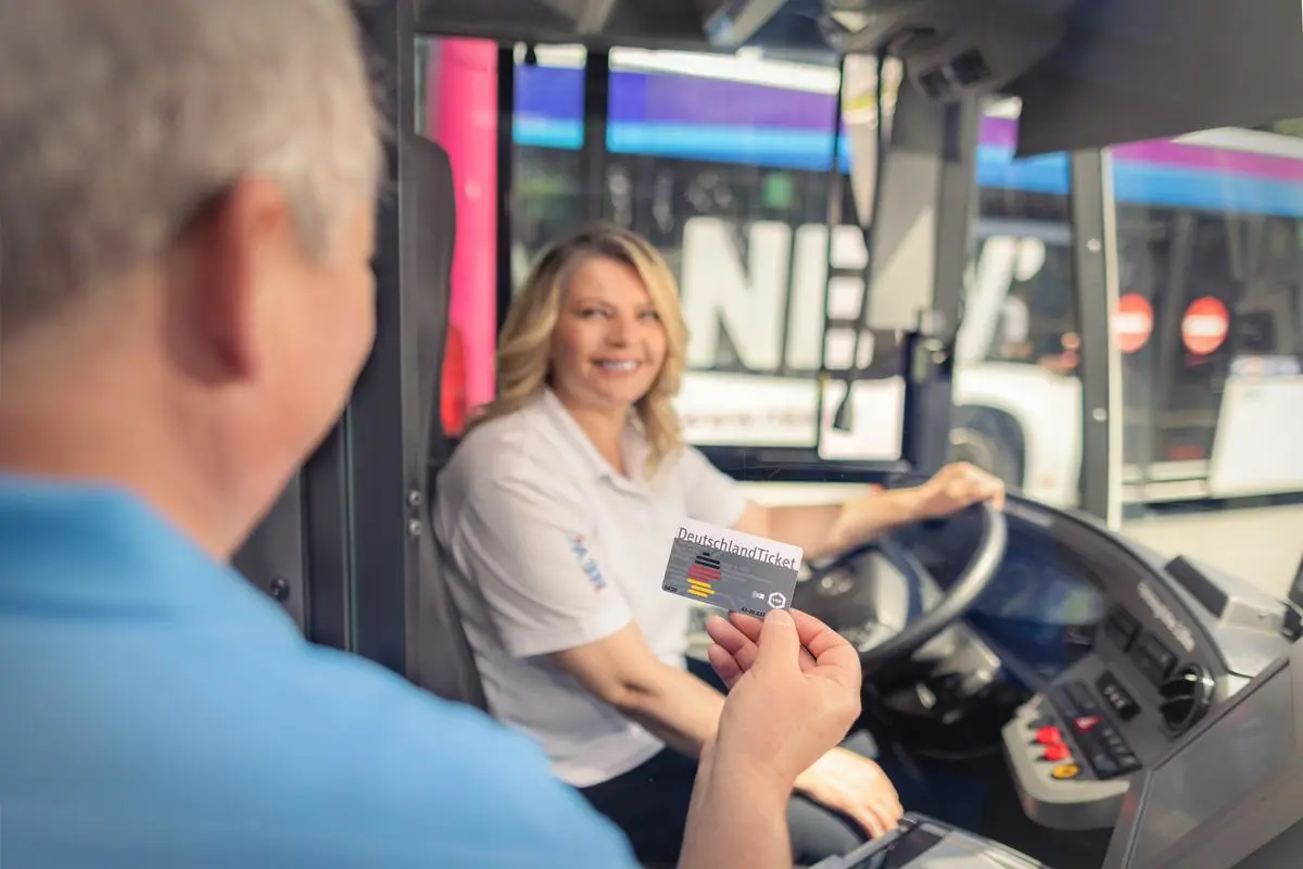Fahrgast zeigt der Busfahrerin sein DeutschlandTicket