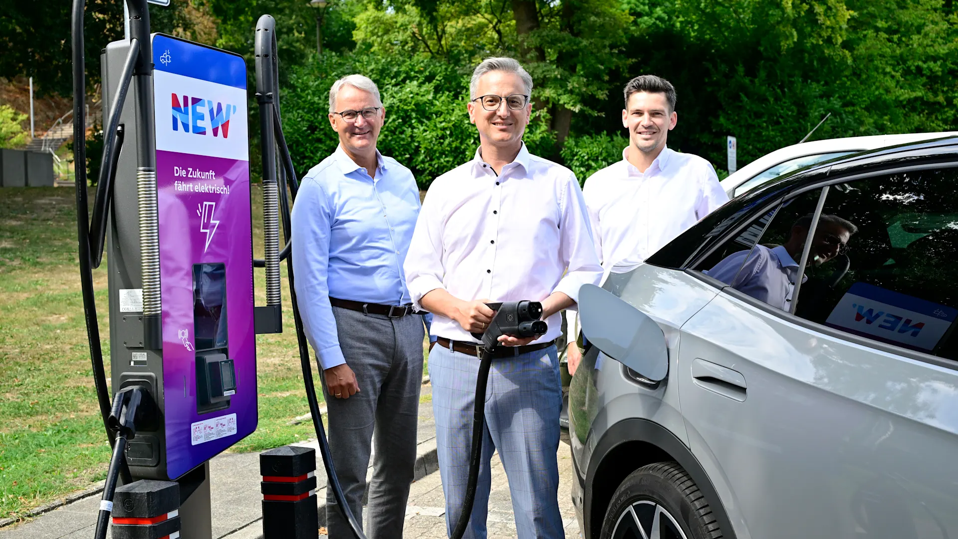 Einweihung E-Ladesaeule Wassenberg Bei einem Zwischenstopp in Wassenberg vollgeladen: Bürgermeister Marcel Maurer freut sich gemeinsam mit den NEWlern Ralf Poll (links außen) und Johannes Vieten (rechts außen) über die zusätzlichen E-Ladesäulen am Bergfried. Credit: NEW AG/Jörg Knappe