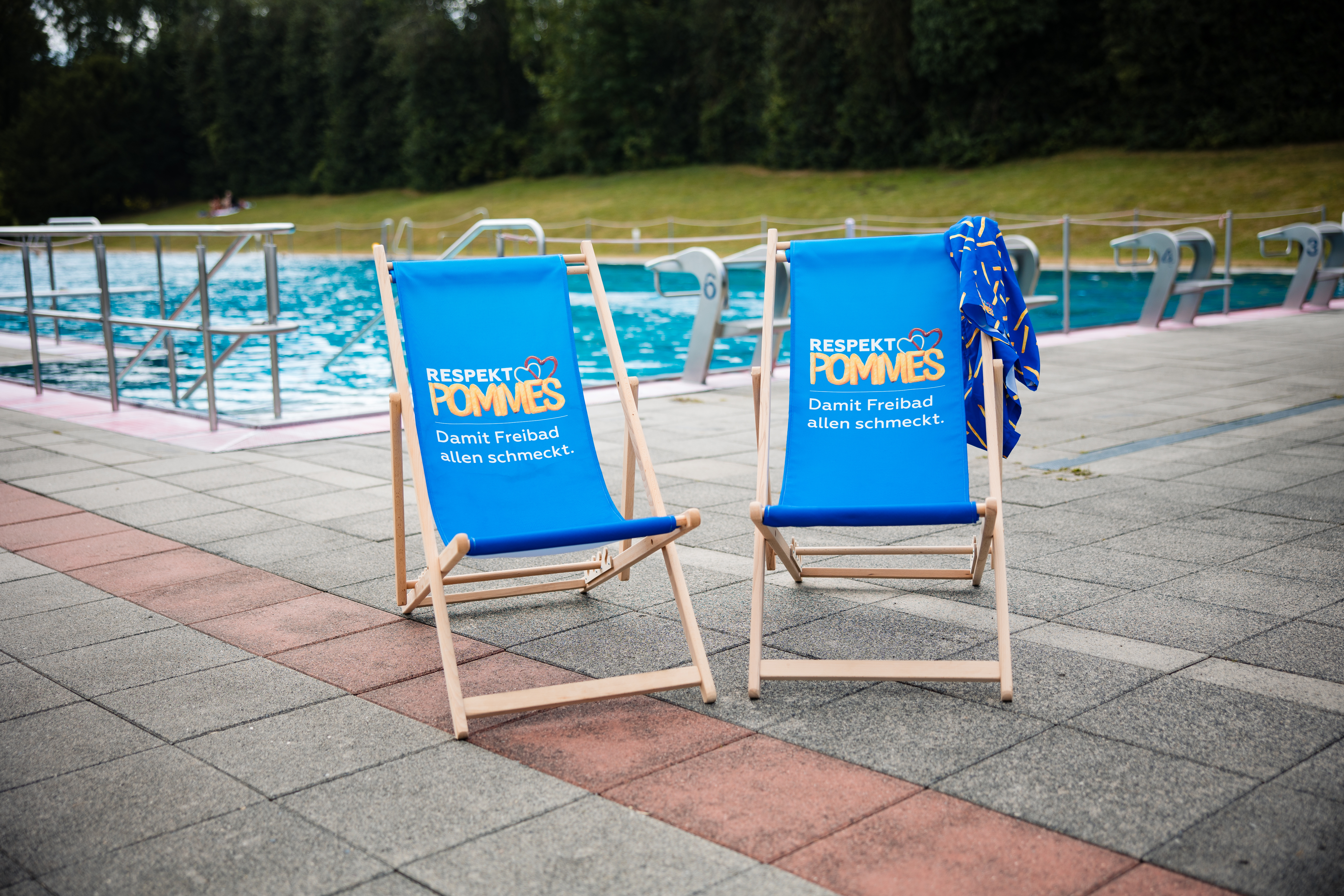 Zwei Liegestuhle vor einem Schwimmbecken im Freibad Volksgarten