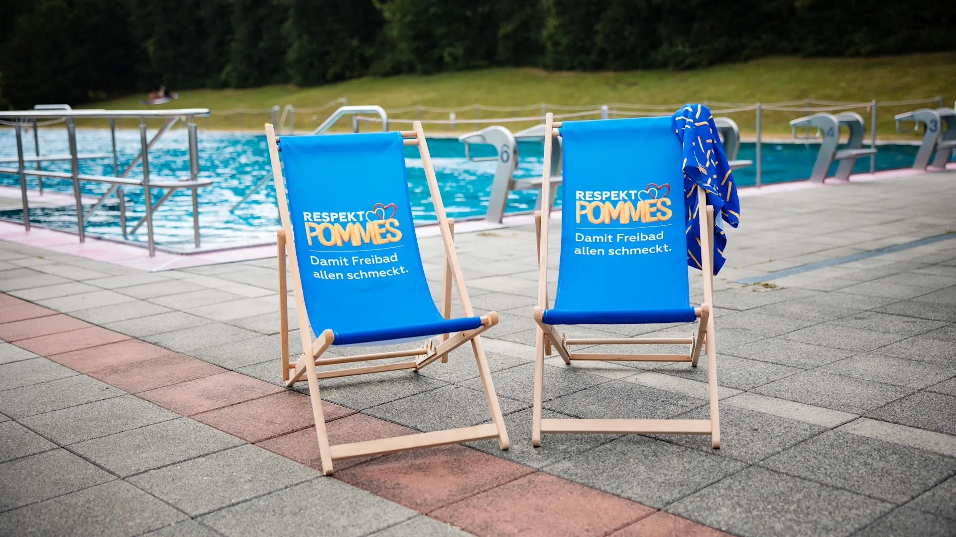 Respektpommes Zwei Liegestuhle vor einem Schwimmbecken im Freibad Volksgarten