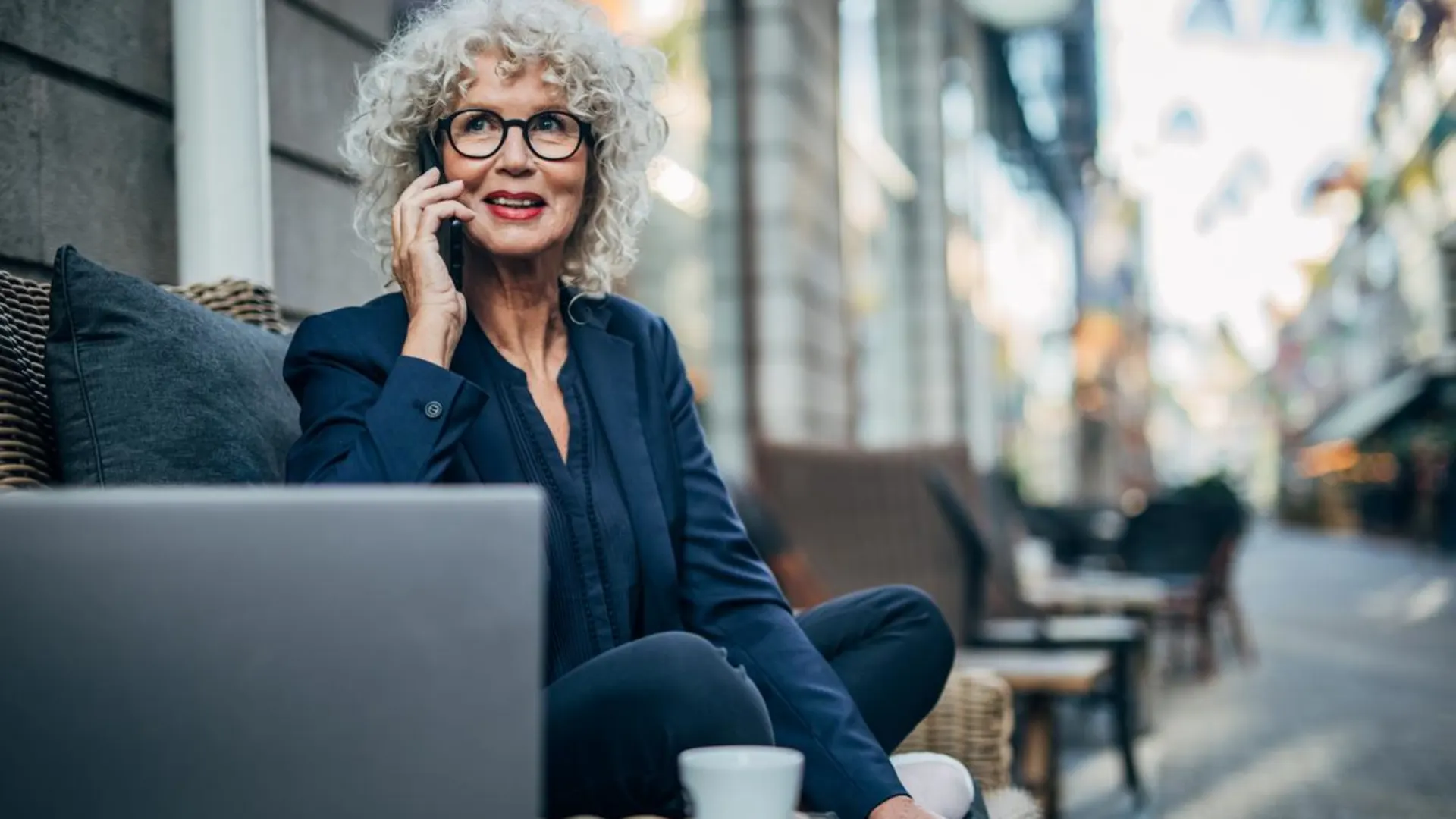 Anruf Sammel Taxi Frau die im Café an einem Laptop sitzt und telefoniert.