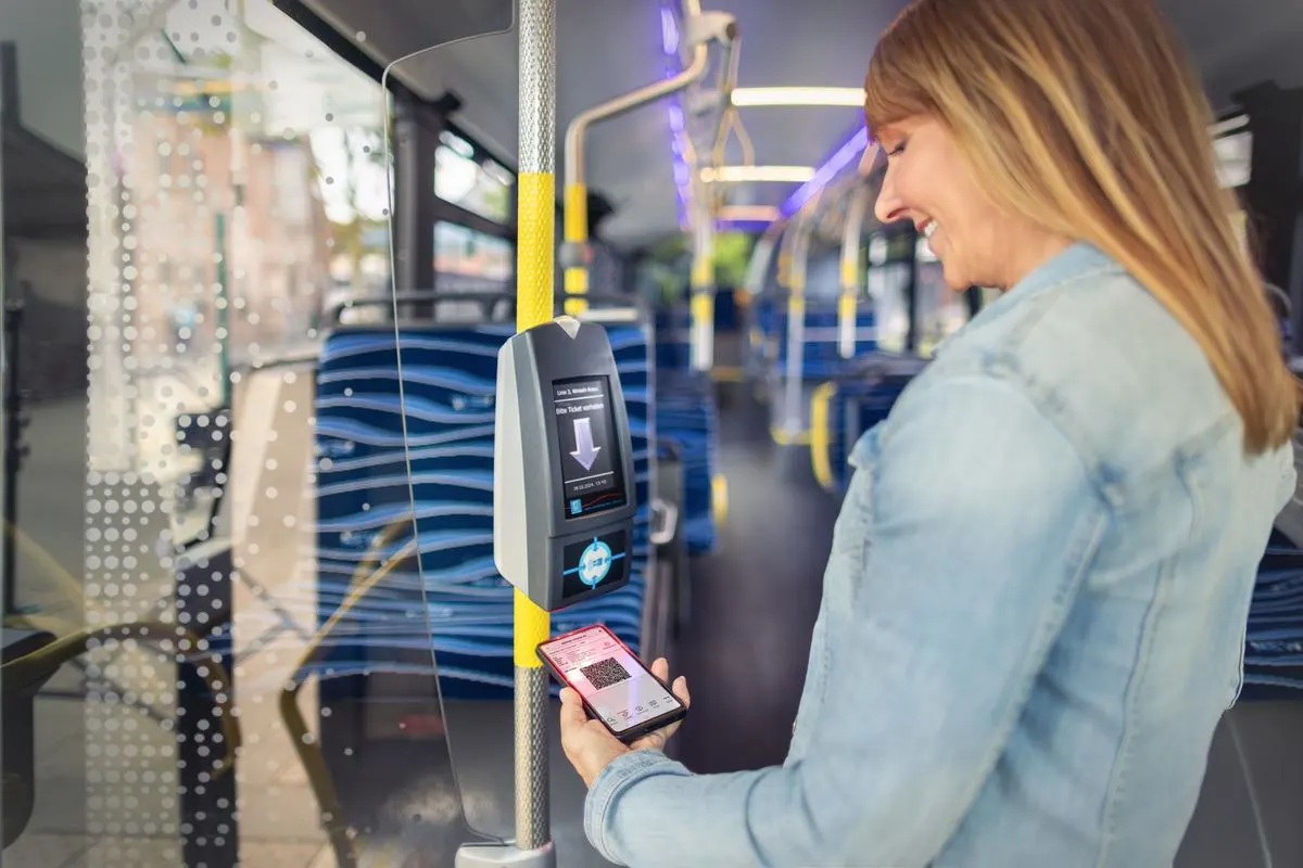 Eine Mitfahrende zahlt im Bus digital mit dem EEZY-Ticket