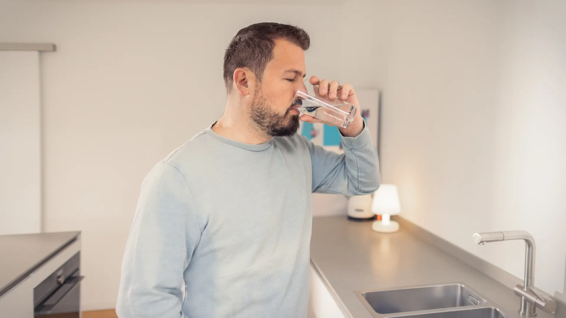 Trinkwasser-von-der-NEW-AG-H8A5811 Ein Mann steht in der Küche und trinkt Leitungswasser aus einem Glas
