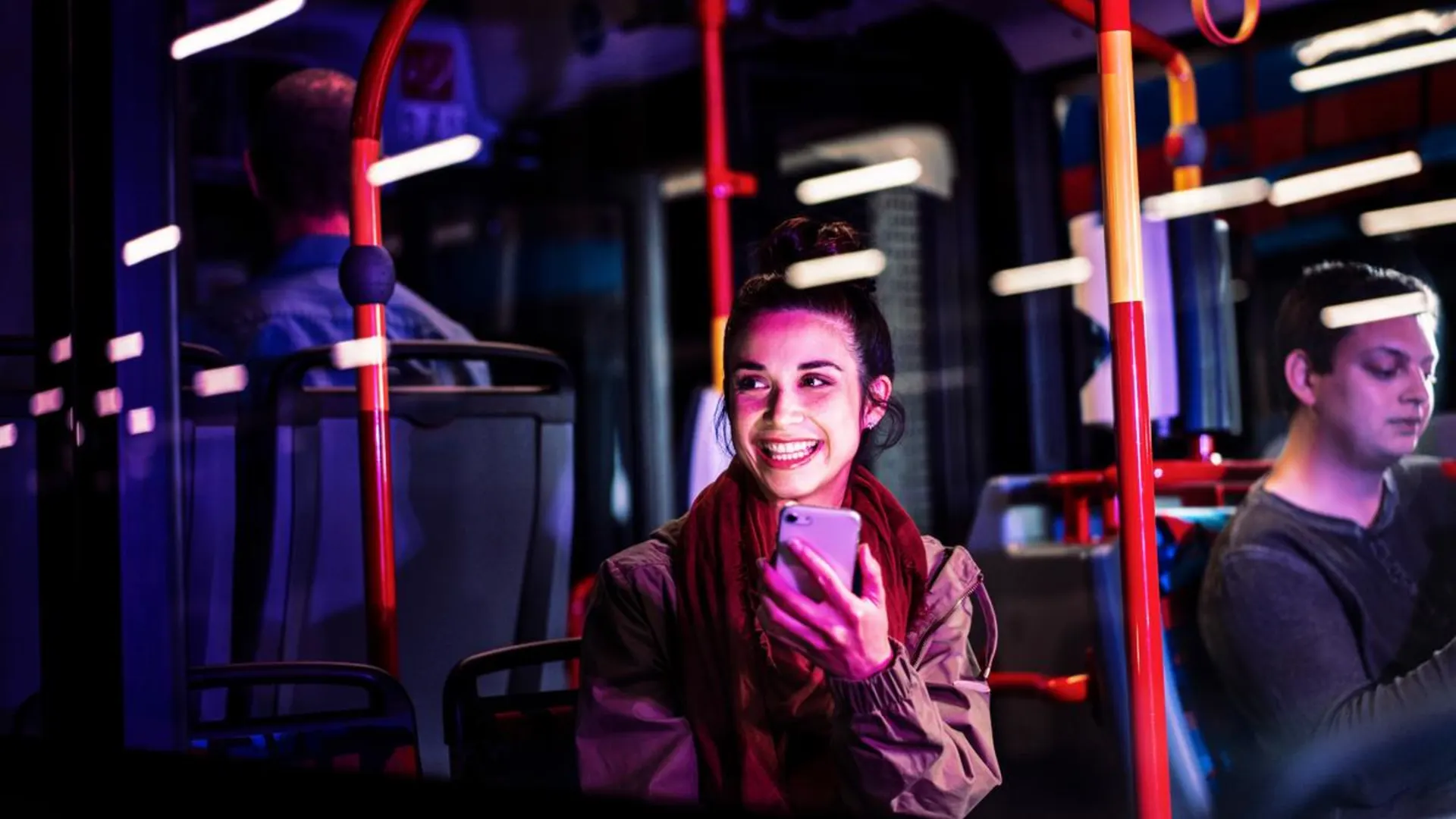 NEW Tickets und Tarife Junge Frau am Handy sitzend im Bus.