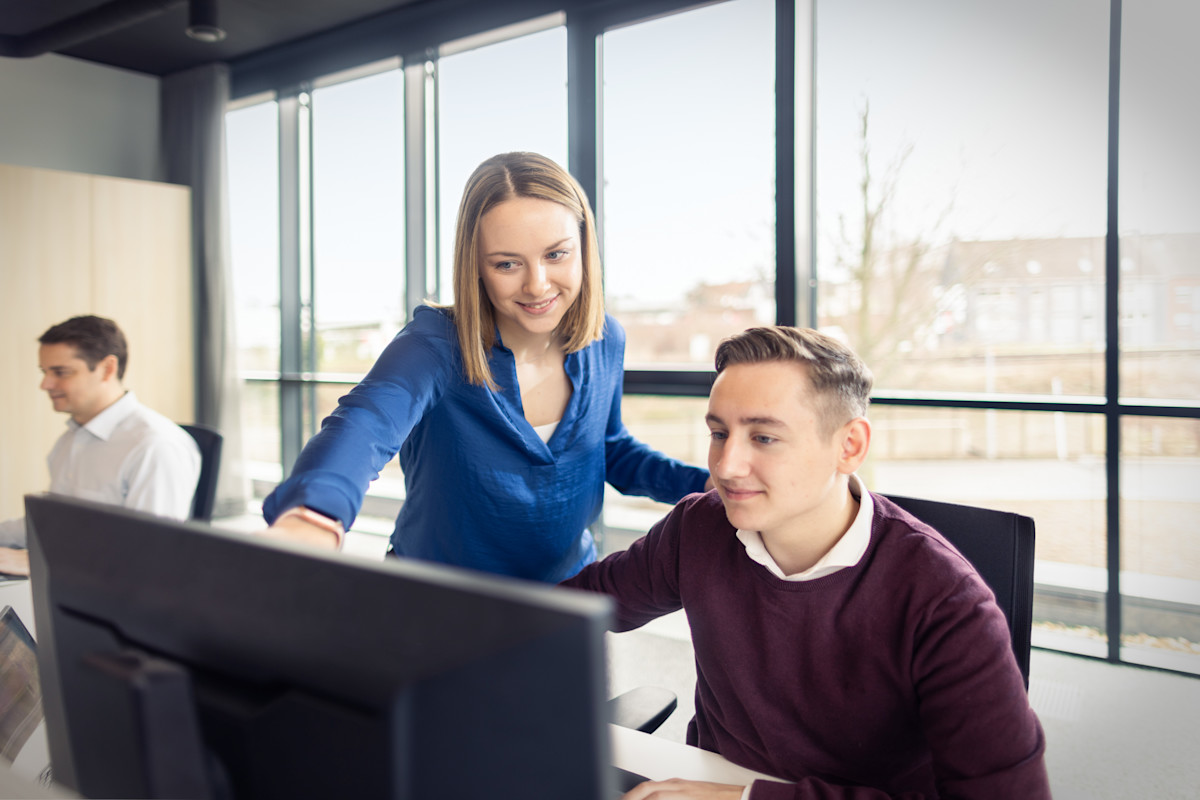 Eine Kollegin zeigt einem Kollegen etwas auf dem Bildschirm.