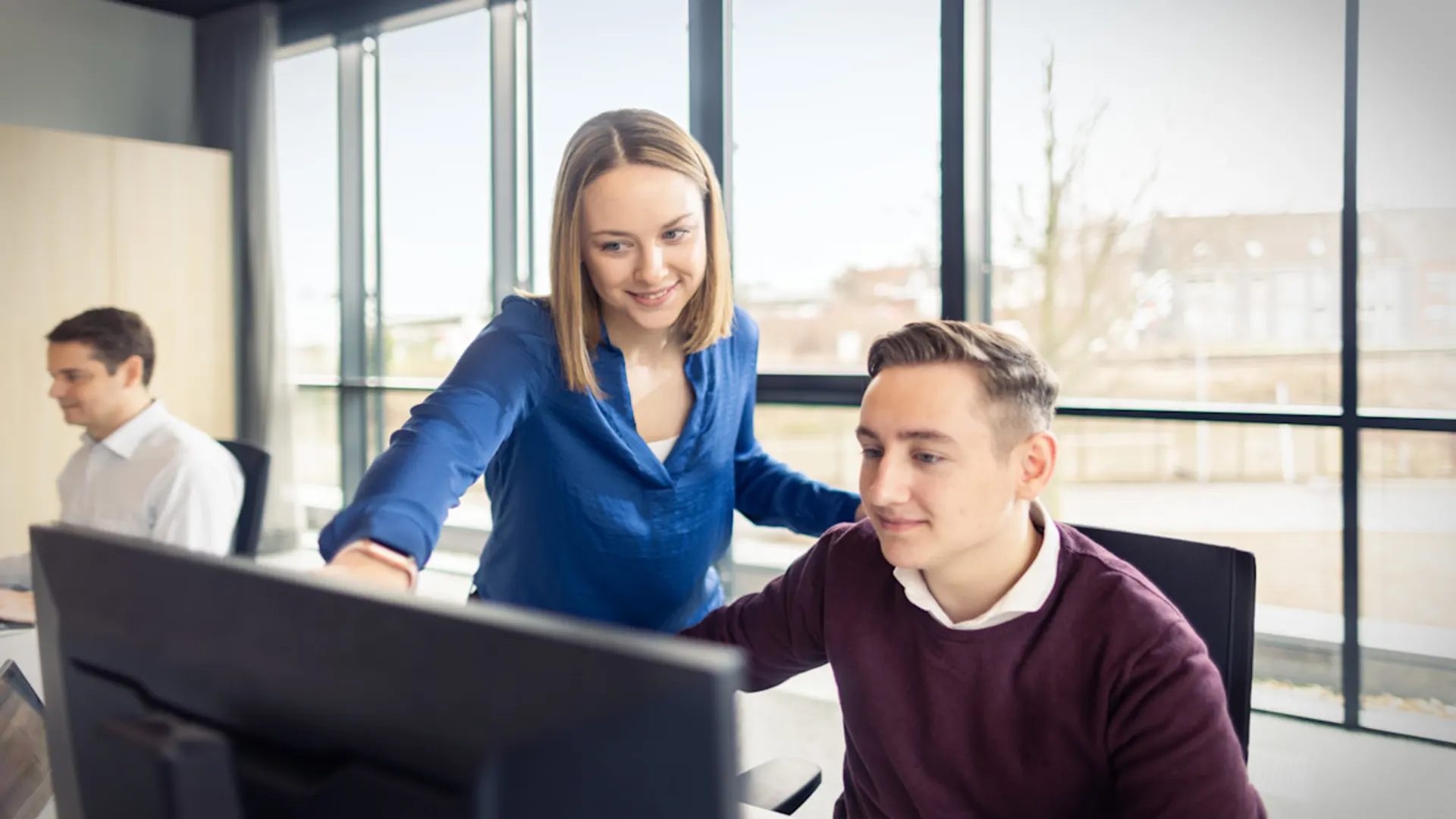 NEW-AG-H8A6693-f-02 Eine Kollegin zeigt einem Kollegen etwas auf dem Bildschirm.