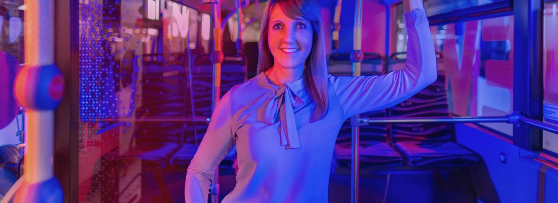 NEW ÖPNV Frau steht im Bus und hält sich an einer Halteschlaufe fest.