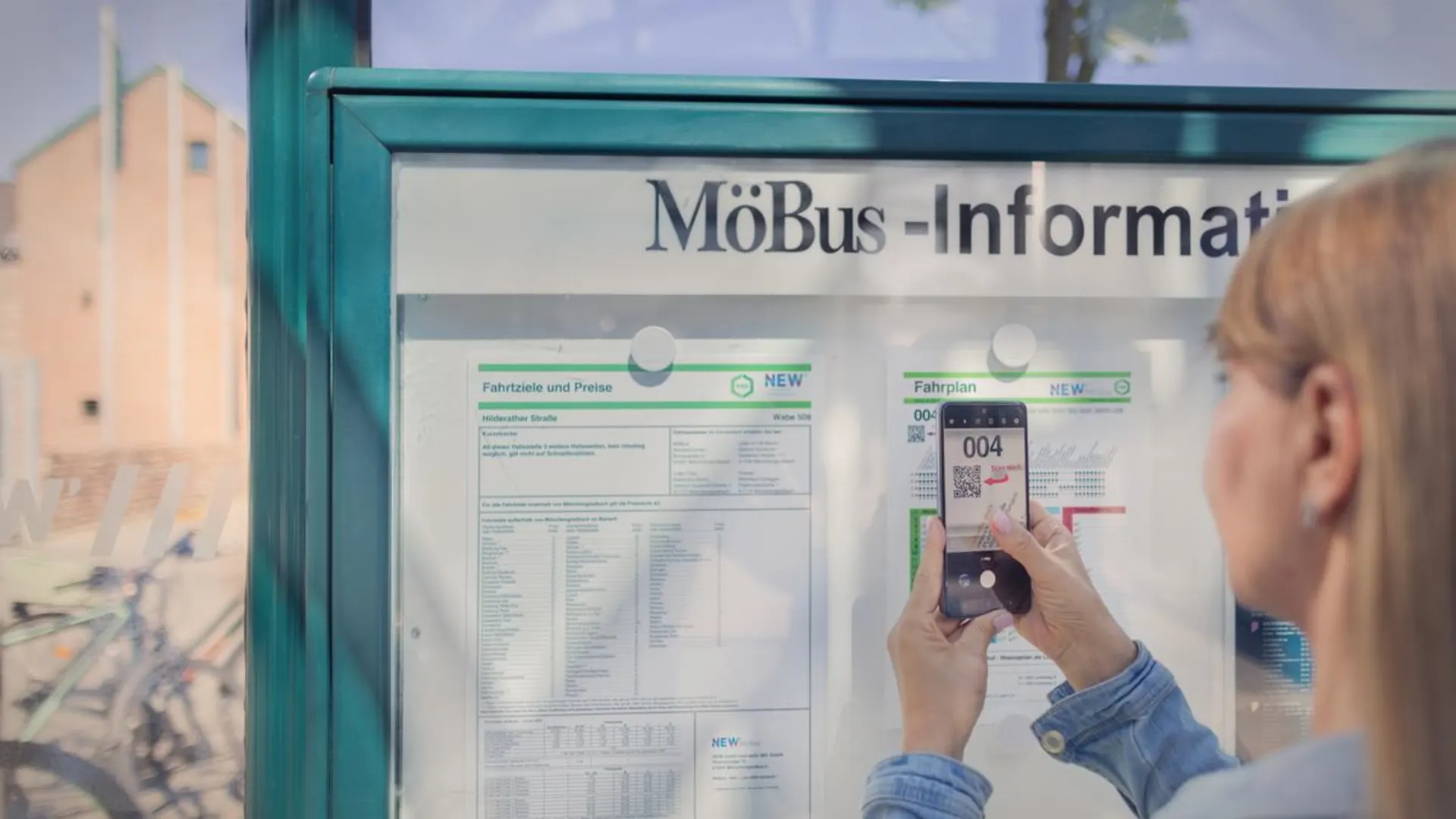 Kundin scannt QR Code an der Haltestelle Kundin scannt QR Code an der Haltestelle