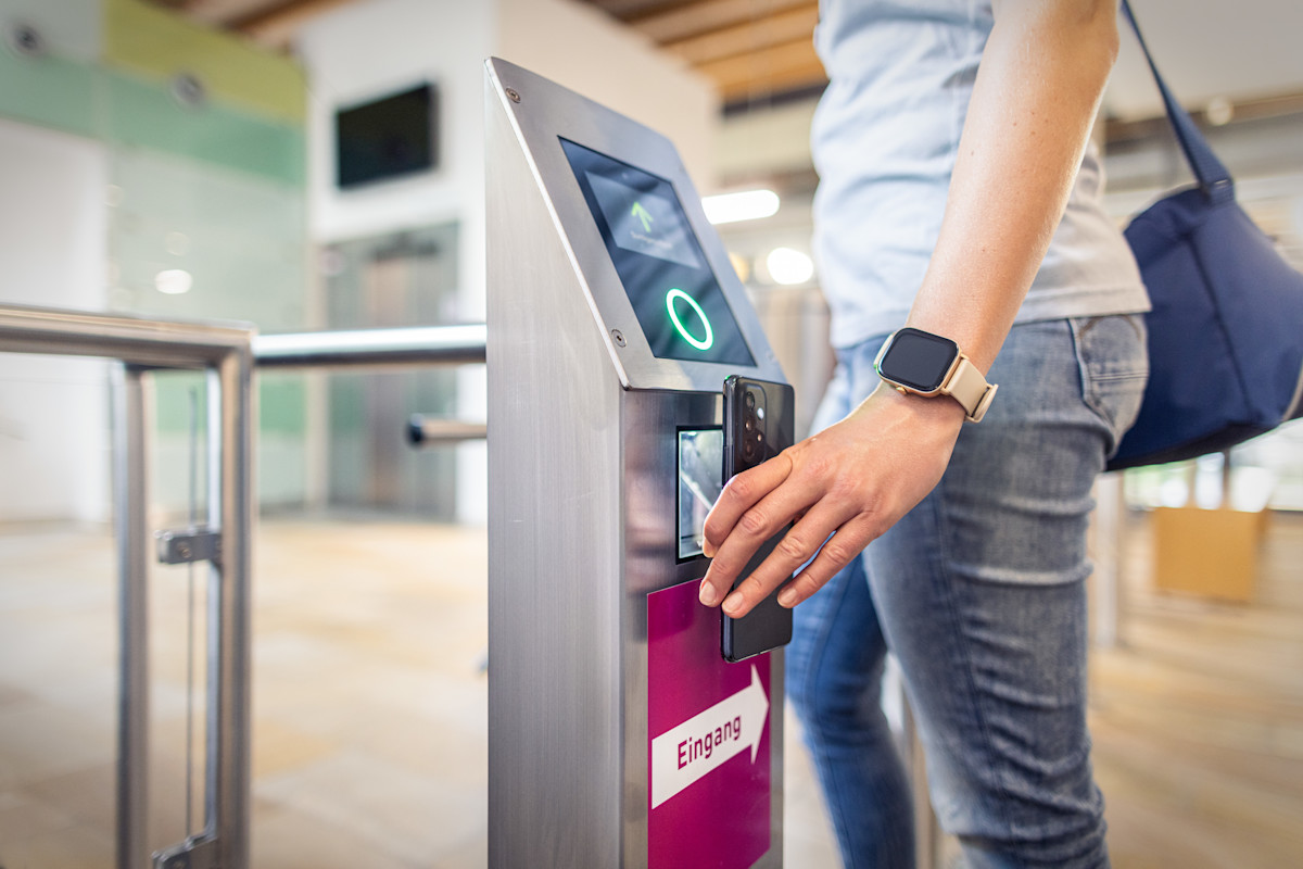 Ein Badegast hält für den digitalen Zutritt das Smartphone vor den Scanner im Eingangsbereich.