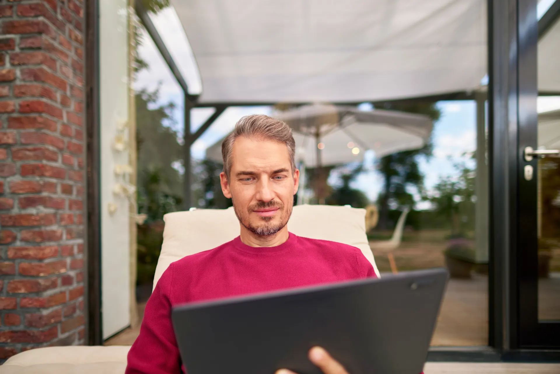 Ein Mann sitzt auf einer Gartenliege mit einem Tablet und schaut sich die Rechnungserlaeterung über die Energietarife bei der NEW Energie an. 