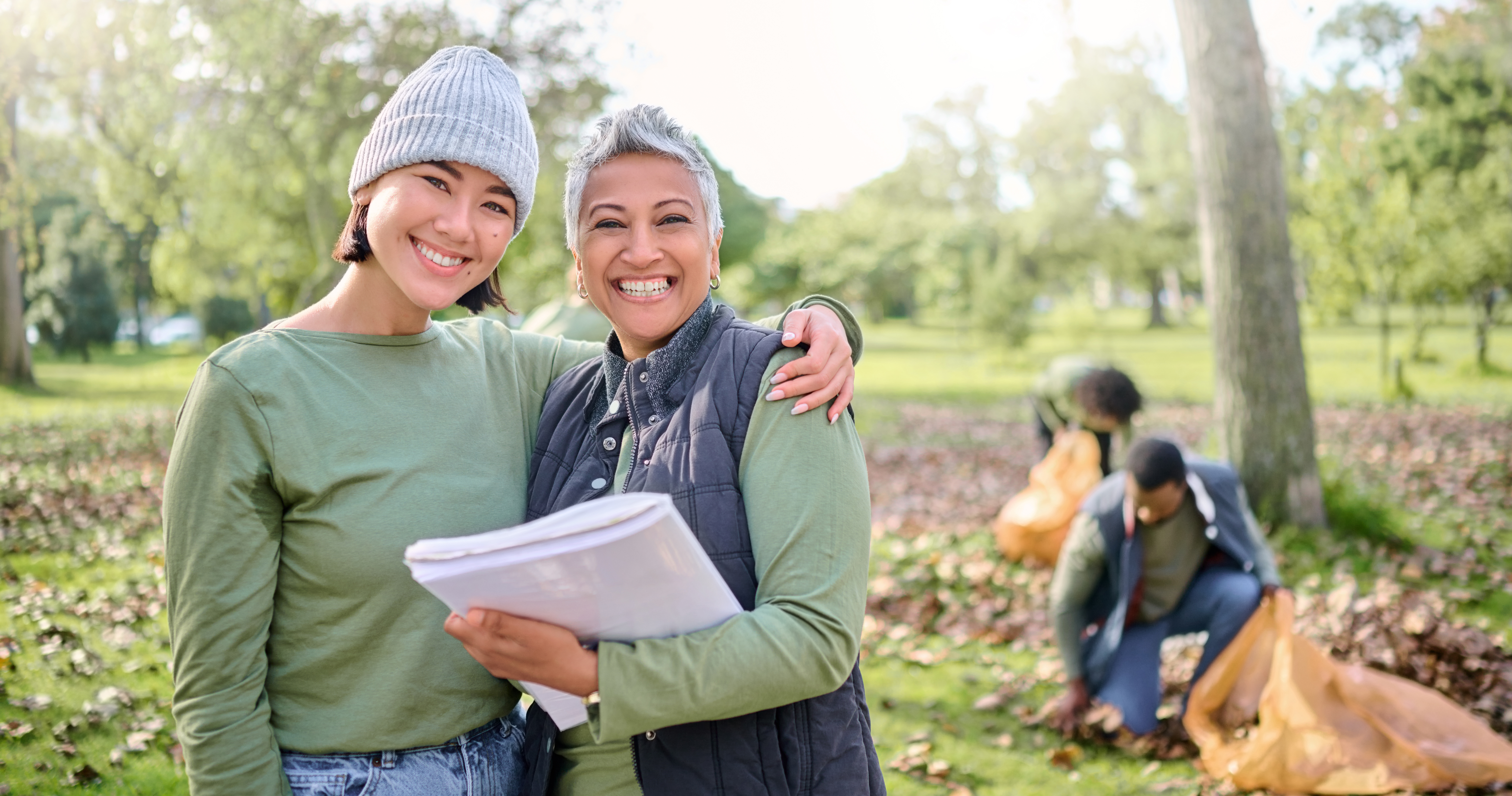 Eine jüngere und eine ältere Frau stehen gemeinsam auf einer Wiese und lächeln in die Kamera.  - Copyright Peopleimages
