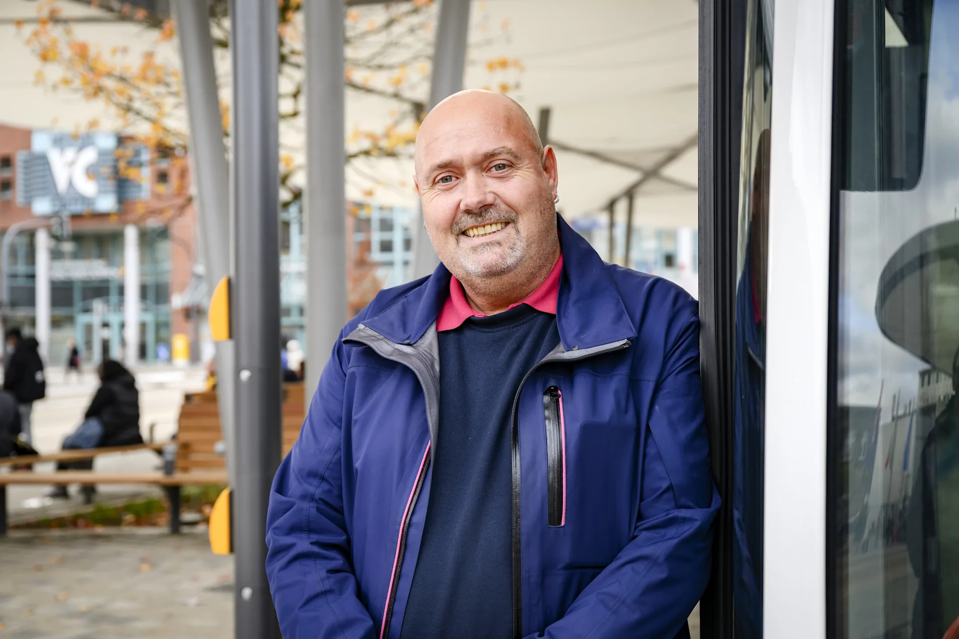 Hans-Dieter steht mit dunkelblauer NEW Kleidung vor einem NEW Bus mit geöffneten Türen
