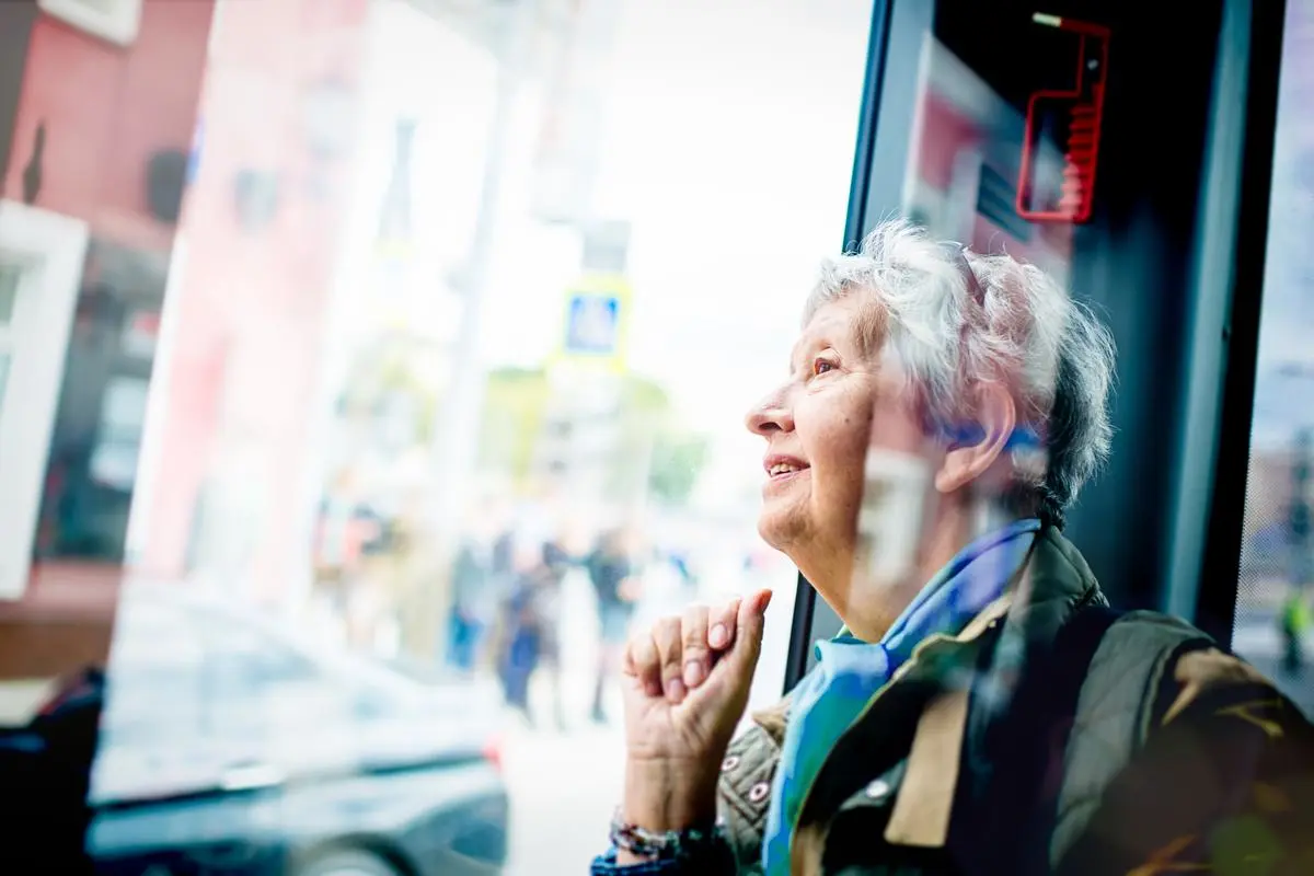 Ältere Dame im Bus, wie sie aus dem Fenster schaut.